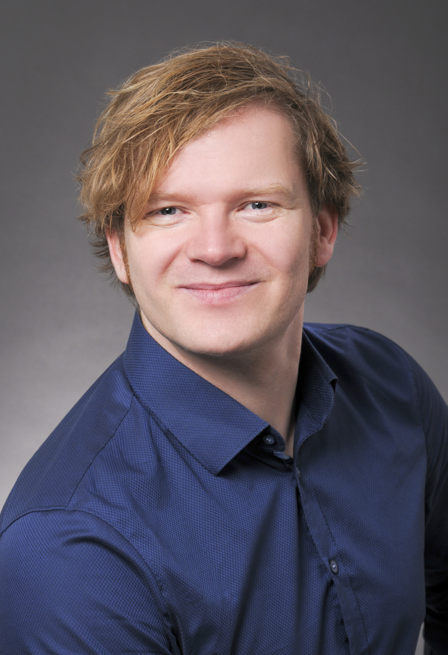 a blond male person facing the front camera with a dark blue shirt